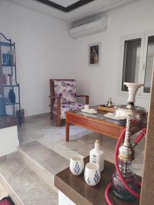 uma sala de estar com uma mesa e uma cadeira em Chambres d'hôtes Conviviales avec piscine privée Chambre Namasté et Chambre Rose des Sables em Djerba