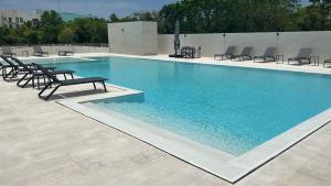 una gran piscina con sillas y una mesa en Lujoso apartamento, Nuevo! en Cancún