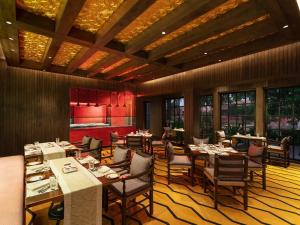 una sala da pranzo con tavoli, sedie e finestre di ITC Grand Goa, a Luxury Collection Resort & Spa, Goa a Utorda