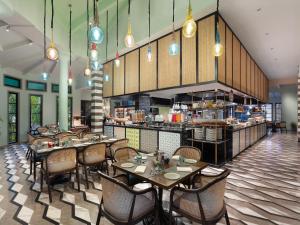 UtordaにあるITC Grand Goa, a Luxury Collection Resort & Spa, Goaのテーブルと椅子のあるレストラン、キッチンが備わります。