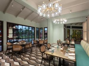 um restaurante com mesas e cadeiras e um lustre em ITC Grand Goa, a Luxury Collection Resort & Spa, Goa em Utorda
