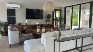 ein Wohnzimmer mit einem Sofa, Stühlen und einem TV in der Unterkunft Lujoso apartamento, Nuevo! in Cancún