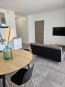 ein Wohnzimmer mit einem Tisch und einem Sofa in der Unterkunft Appartement neuf, rez-de-jardin in Lucciana