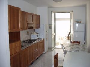 a kitchen with wooden cabinets and a white refrigerator at Stanze villa Morosini in Torre San Giovanni Ugento