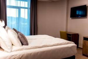 1 dormitorio con 1 cama blanca y ventana en Hotel IN, en Banja Luka