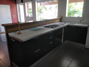 a kitchen with a stove and a sink and two windows at Belle Villa au cœur de la Gwada in Le Gosier
