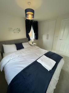 um quarto com uma cama grande e um cobertor azul em Luxurious Apartment in Brooklands em Milton Keynes