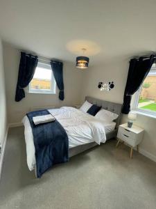 a bedroom with a large bed and two windows at Luxurious Apartment in Brooklands in Milton Keynes