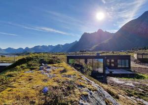 una casa en una colina con montañas en el fondo en Luxury Lodge with jacuzzi and sauna en Kleppstad