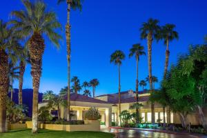 a house with palm trees in front of it at Courtyard by Marriott Palm Springs in Palm Springs