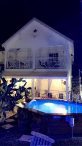 - une piscine en face d'une maison la nuit dans l'établissement Hébergements, restauration proche de la plage Caravelle, à Sainte-Anne