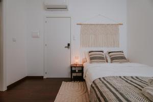 Porto Hostel Cúpula في بورتو: غرفة نوم بيضاء مع سرير وطاولة مع مصباح