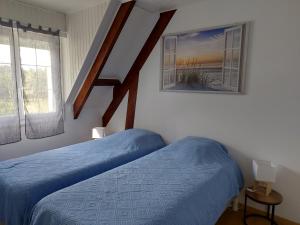 a bedroom with two beds with blue sheets and windows at Le Sanctuaire in Missillac