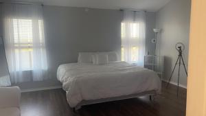 een slaapkamer met een bed met witte lakens en ramen bij Hme Away from Hme in San Antonio