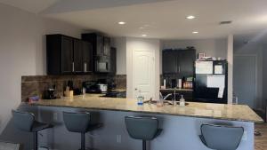 a kitchen with black cabinets and a counter with chairs at Hme Away from Hme in San Antonio