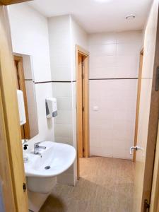 y baño blanco con lavabo y ducha. en Hostel Acacias en Madrid