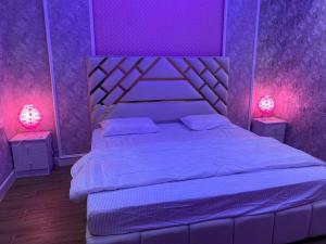 - une chambre violette avec un lit et deux lampes dans l'établissement شاليه العماريه, à Yanbu Al Bahr