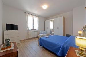 una camera con letto blu e televisore di CASA REFENERO a Torrita di Siena