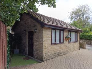un pequeño edificio de ladrillo con puerta y ventana en Lister Park Bradford Stylish 1bed Coach House - Quiet & Tranquil Cottage & Parking en Shipley
