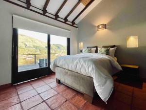 1 dormitorio con cama grande y ventana grande en Casa de las Flores- Buganvilias, en Villa de Leyva