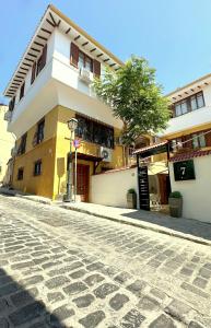 a yellow and white building on a cobblestone street at 7PocketHouse in Thessaloniki