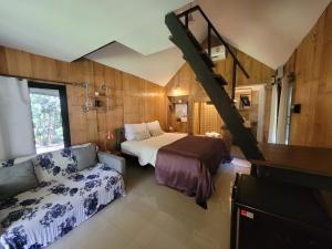 a bedroom with a bed and a couch and a staircase at Brook Cottage in Ban Khanong Phra Klang (1)