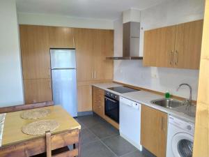 eine Küche mit Holzschränken und einem weißen Kühlschrank in der Unterkunft Vila María in Castrelo de Miño