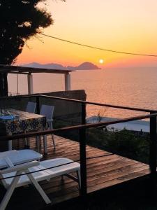 una terraza con mesa, sillas y puesta de sol en Ponzamania Appartamenti Ponza ,,Blumarine'', en Ponza