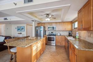 a large kitchen with wooden cabinets and a ceiling fan at Trillium 2A - Premier in St. Pete Beach