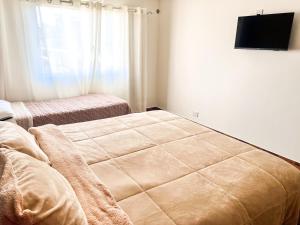 1 dormitorio con 2 camas y TV de pantalla plana en Casa entera con patio, parrilla y cochera en Lomas de Zamora