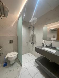 ein Badezimmer mit einem WC, einem Waschbecken und einem Spiegel in der Unterkunft جوهرة البحر للشقق المخدومة in Dschāzān