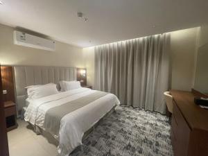 Schlafzimmer mit einem großen weißen Bett und Vorhängen in der Unterkunft جوهرة البحر للشقق المخدومة in Dschāzān