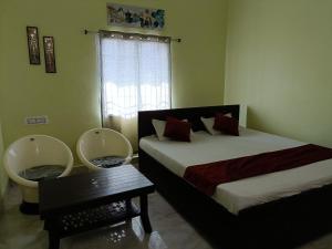 a bedroom with two beds and a table and a window at Hotel Narayani in Rājgīr