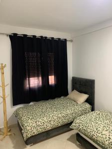 ein Schlafzimmer mit 2 Betten und einem schwarzen Vorhang in der Unterkunft Appartement cosy et pratique in Oujda