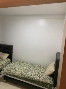 Bett in einem Zimmer mit einer weißen Wand in der Unterkunft Appartement cosy et pratique in Oujda
