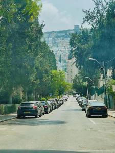 een rij auto's geparkeerd aan de kant van een straat bij Estrela Mares Haifa in Haifa