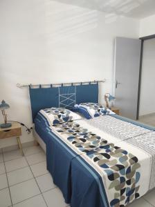 a bedroom with a bed with a blue and white comforter at La Coraline Standing in Kourou