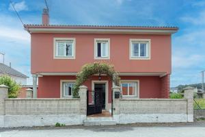 una casa rosa con una puerta negra en Casa Herminia en Coristanco