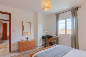 a bedroom with a bed and a desk and a window at Casa Herminia in Coristanco