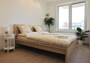 a bedroom with a large bed with two windows at Luxury Grand Apartments by Bratislavatrip in Bratislava