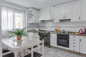 uma cozinha com armários brancos e uma mesa com um vaso de plantas em Casa Herminia em Coristanco