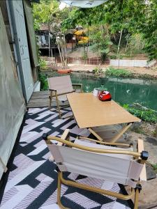 een patio met een tafel en 2 stoelen op een veranda bij Brook Cottage in Ban Khanong Phra Klang (1)
