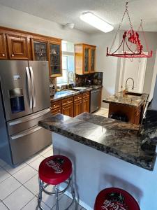 a kitchen with a stainless steel refrigerator and two red bar stools at BEAUTIFUL VACATION HOME RENTAL WITH TROPICAl STYLE HEATED POOL & HOT TUB in Alvin