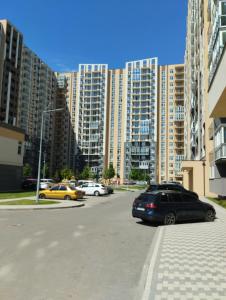 Una calle de la ciudad con coches aparcados delante de edificios altos. en Номер-студіо "Міні Феофанія" Заболотного 148, Кришталеві Джерела, лікарня, пораненим воїнам -10", en Kiev
