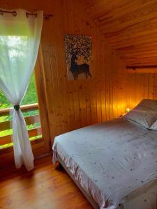 een slaapkamer met een bed in een kamer met een raam bij Gite Le Chalet SaintAnthème / Prabouré in Saint-Anthème