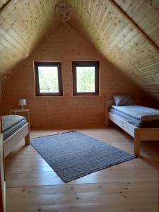 a room with two beds and two windows in a attic at Domek wypoczynkowy in Wydminy