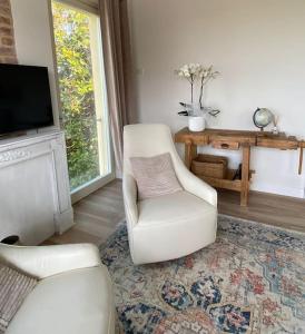 a living room with a white chair and a television at Vita Bella in Castagnole Monferrato