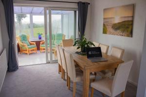a dining room with a table with a laptop on it at 3-bedroom home with Breakfast, PS4 & Private parking in Swansea