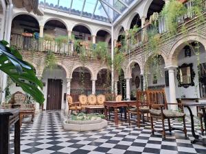 Hostal Palacio del Corregidor في قرطبة: غرفة مع كراسي وطاولات في مبنى