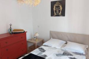 ein Schlafzimmer mit einem Bett mit einer roten Kommode und einem Bild in der Unterkunft calme rez-de-chaussée 2 Chambres 70 M2 in Roanne